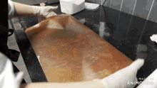 a person wearing gloves is holding a piece of brown paper on top of a counter .