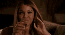 a woman is sitting on a couch drinking from a glass .