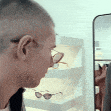 a man wearing glasses is looking at his reflection in a mirror