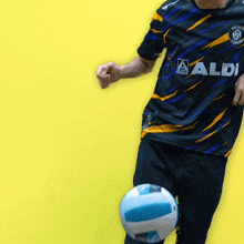 a man wearing an aldi shirt kicking a ball
