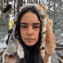 a woman wearing a fur hooded jacket looks at the camera
