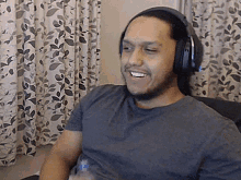 a man wearing headphones is smiling in front of a window