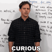 a man is standing in front of a white board with the word curious written on it