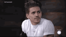 a man in a white shirt is sitting in front of a ao vivo logo