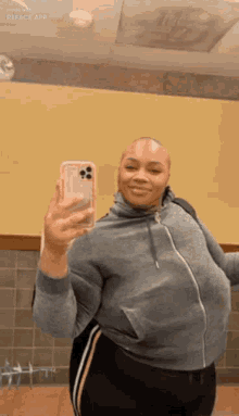 a woman is taking a selfie in front of a mirror with her phone .