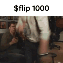 two men are sitting on a couch and one of them is holding a dollar bill .