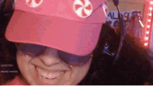 a woman wearing a pink hat and sunglasses is smiling and wearing a headset .