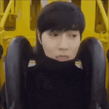 a man in a black turtleneck is riding a roller coaster and making a funny face