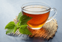 a cup of tea with green leaves on a cloth