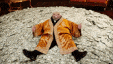 a man in a robe is laying on a pile of cash