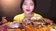 a woman is eating a bowl of soup with chopsticks .