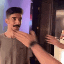 a man with a mustache is touching another man 's face .
