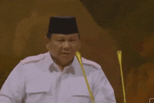 a man in a white shirt is giving a speech and the word hidup is above him