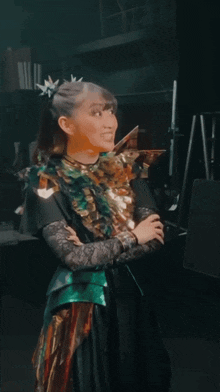 a woman in a green and gold outfit is standing in a dark room