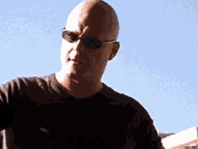 a man wearing sunglasses and a black shirt looks at the camera