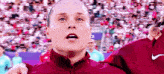 a woman in a red nike jacket stands in front of a crowd .