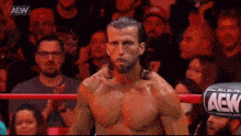 a wrestler without a shirt is standing in a ring with a crowd watching .