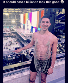 a shirtless man wearing a chain around his neck stands in front of a stadium