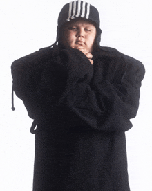a person with their arms crossed wearing a black hat