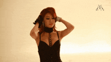 a woman in a black corset is standing in front of a white wall with the letter m on it