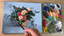 a person is painting flowers on a canvas with a palette in the background