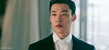a man in a suit and white shirt is wearing a headset and looking at the camera .