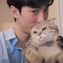 a young man is holding a cat in his arms .