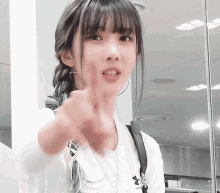 a woman wearing a white under armour shirt points her finger at the camera