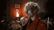 a man in a red jacket is sitting on a couch in a dark room
