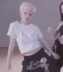 a woman is wearing a white crop top and black sweatpants that say j'ai la sensation