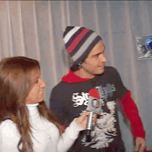 a woman is holding a microphone next to a man wearing a shirt that says ' jesus '