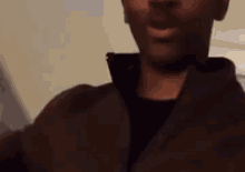 a close up of a man wearing a brown jacket and black shirt .