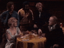 a group of people sitting at a table with the words " i 'm extremely wealthy " in yellow letters