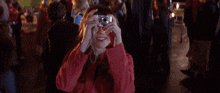 a woman in a red jacket is taking a picture with a camera at a carnival