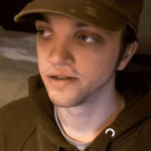 a close up of a man wearing a hat and a sweatshirt