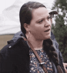 a woman wearing a braided ponytail and hoop earrings is talking to someone