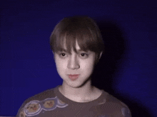 a young man wearing a brown shirt with a pattern on it looks at the camera