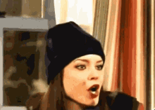 a woman wearing a black beanie has her mouth wide open