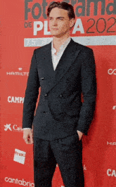 a man in a suit stands in front of a red carpet that says fotoama de pla 202