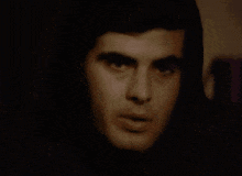 a close up of a man 's face in a dark room with a lamp in the background .