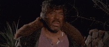 a man with a beard is standing in the dark and looking at the camera
