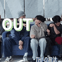 a group of people are sitting on a blue couch with the word out written above them