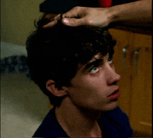 a close up of a young man 's head with a hand on it