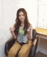 a woman sitting in a chair with her hands in her fist