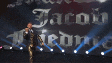 a man in a suit stands in front of a sign that says aew on it