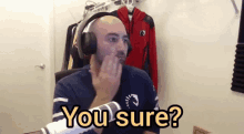 a man wearing headphones says " you sure " while sitting in front of a microphone