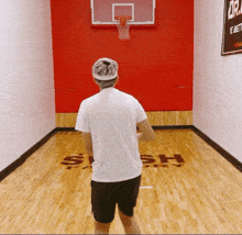 a man stands on a basketball court that says slash