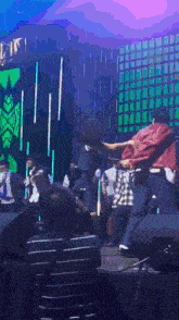 a man in a red shirt is dancing on a stage with a crowd watching