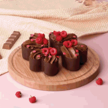 a wooden cutting board topped with chocolate cupcakes with raspberries on top