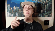 a young man wearing a hat is giving a thumbs up sign